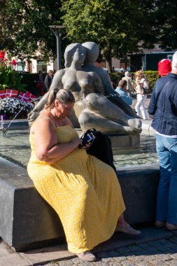 Copenhagen, Denmark  A woman sits at a fountain with phone at the Frederiksberg Radhus to welcome Queen Margrethe II of Denmark.