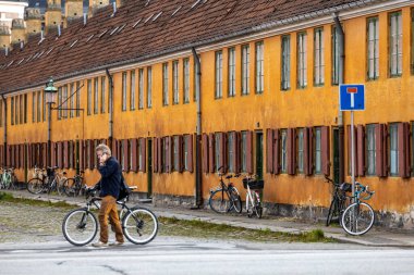 Copenhagen, Denmark,  A man walks with a bike in Nyboder, a historic row house district of former Naval barracks planned and first built by Christian IV