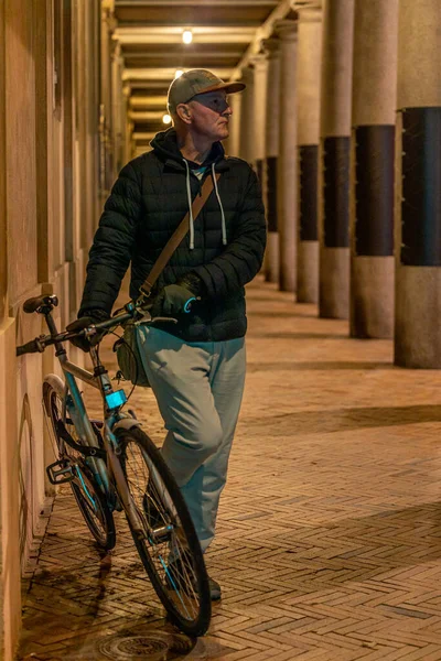 Copenhagen, Denmark A man poses next to a bicycle in an arched alleyway on Stormgade