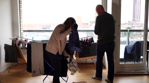 デンマークのコペンハーゲン夫婦は居間の棚の上で洗濯を一緒にしています — ストック動画