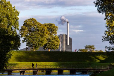 Kopenhag, Danimarka Kastellet parkında yürüyen insanlar ve KopenHill enerji santralinin manzarası.