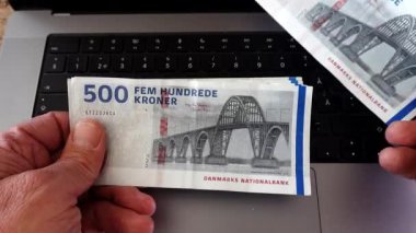 Bir adam 500 Danimarka kronu sayıyor, Dansk krone, bir bilgisayarın üzerine notlar.. 