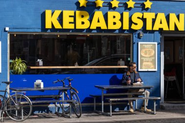 Kopenhag, Danimarka. Kebabistan adında bir kebap restoranı zinciri ve açık havada takılan bir adam..