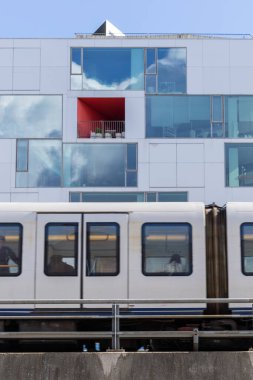 Kopenhag, Danimarka Orestad bölgesindeki yükseltilmiş metro hattı ve modern bir bina..