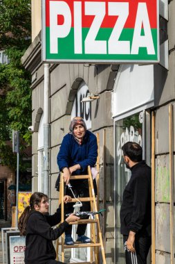 Kopenhag, Danimarka Bir pizza restoranının sahipleri dükkanlarının ön cephesini boyar.