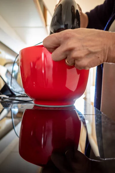 An electric food mixer is used to make fresh frosting for a cake.