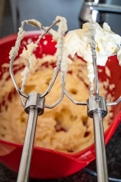 A close-up of an electric food mixer used to make fresh frosting for a cake.