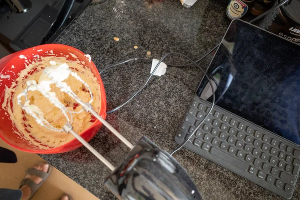 An electric food mixer is used to make fresh frosting for a cake and a tablet computer.