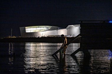 Kopenhag, Danimarka. Bir kişi sabahın erken saatlerinde Öresund 'da Danimarka Ulusal Akvaryumu, Den Blla Gezegeni ve Mavi Gezegen' in önünde yıkanır..