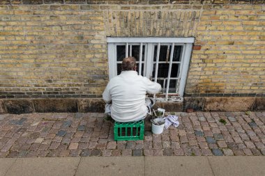 Kopenhag, Danimarka 'da bir adam binanın dış tarafına pencere boyuyor..