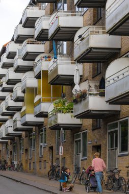 Kopenhag 'ın kuzeyindeki Utterslev bölgesinde bir caddede Kopenhag, Danimarka Evi cephesi ve balkonları ve yürüyen insanlar.,