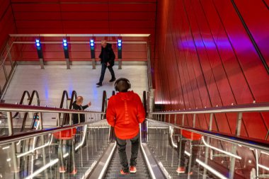 Kopenhag, Danimarka. Kulaklıklı ve kırmızı ceketli bir adam Norrbro 'daki kırmızı metro istasyonuna giriyor..