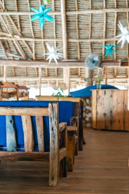 Kafenin çatısının altındaki ahşap masalar. Kendwa, Zanzibar, Tanzanya 'daki restoranın otantik iç mekanı.