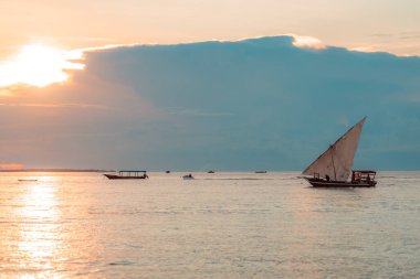 Hint Okyanusu 'nun sularında gün batımında tekne ve balıkçı teknesi. Zanzibar, Tanzanya