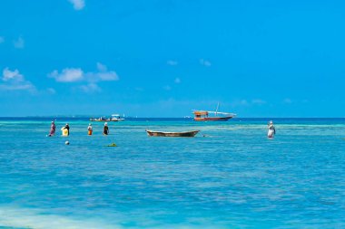 Balıkçı teknesi ve yerli kadınlar gelgit sırasında Hint Okyanusu 'nun sularında. Zanzibar, Tanzanya