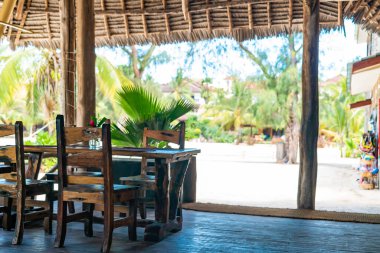 Kafenin çatısının altındaki ahşap masalar. Kendwa, Zanzibar, Tanzanya 'daki restoranın otantik iç mekanı.
