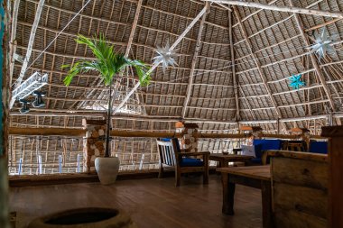 Kafenin çatısının altındaki ahşap masalar. Kendwa, Zanzibar, Tanzanya 'daki restoranın otantik iç mekanı.