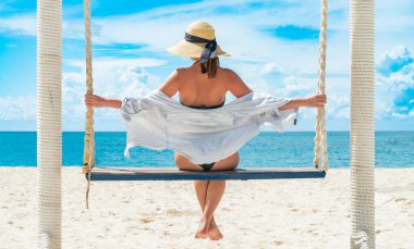 Güzel Hint Okyanusu tropik plajının önünde şapkalı genç bir kadın salıncak sallıyor. Zanzibar tatili