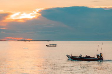 Balıkçıyla birlikte balıkçı teknesi, Hint Okyanusu 'nda manzaralı bir günbatımında eve dönüyor. Zanzibar, Tanzanya.