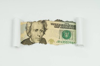 İş ve finans kavramı. Bir kağıt parçasının yırtık deliğinde 20 dolarlık bir banknotun görüntüsü görünür.