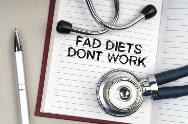 Tıp konsepti. Masanın üzerinde bir steteskop, bir kalem ve üzerine yazdığı bir defter var - Fad Diets Don 't Work