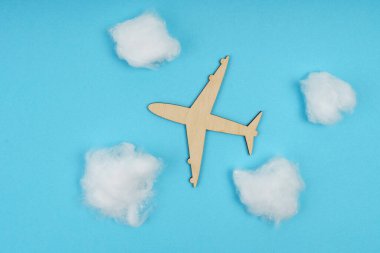 İş ve turizm kavramı. Ahşap bir uçak bulutların arasında gökyüzünde uçuyor - pamuk yünü. Mavi bir arkaplanda izole edilmiş.
