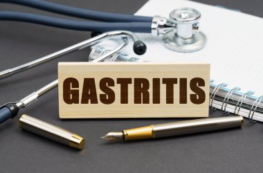 Tıp konsepti. Masanın üzerinde bir defter, bir steteskop ve GASTRITIS yazılı bir tabela var.