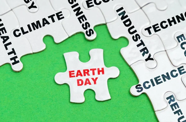 Environmental concept. On a green background, white puzzles with text, a puzzle with the inscription - earth day