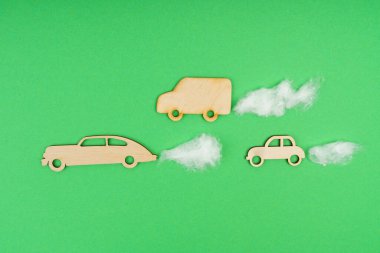 Çevresel konsept. Karbondioksit emisyonu olan ahşap arabalar, pamuk. Yeşil bir arkaplanda izole edilmiş.