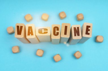 Tıp konsepti. Mavi arka planda, tahta küpler ve yazılı Jenga - VACCINE