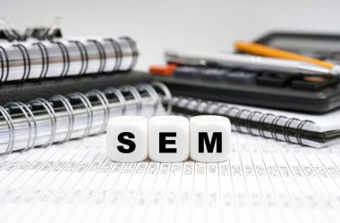 İş ve finans kavramı. Masanın üzerinde, ofis eşyalarının arasında, yazıyla birlikte küpler - SEM