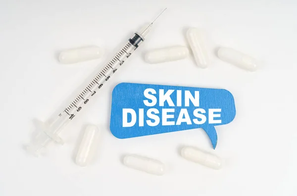 医学と健康の概念 白い背景の丸薬では 注射器と碑文の青いプレート スキン病 — ストック写真