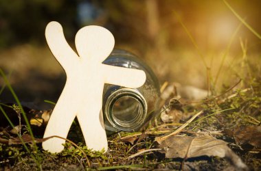 Ekoloji ve tıp konsepti. Tahta bir adam, cam bir alkol şişesini işaret eder..