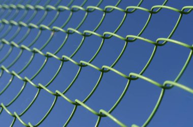 Güvenlik ve doku. Mavi gökyüzünün arka planında, hücresel metal ağ yeşildir..