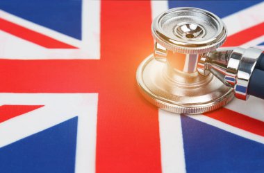 Tıp ve ekonomi kavramı. Büyük Britanya bayrağında bir steteskop var.