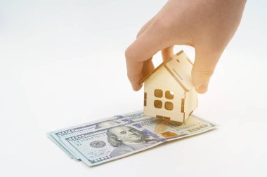 Gayrimenkule yatırım. Beyaz arka planda dolar yatar, adamın biri üzerine ev koyar. Beyazda izole edilmiş.