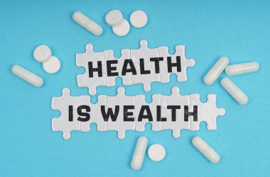 Tıp konsepti. Mavi arka plan hapları ve yazıtlardaki bulmacalarla Sağlık Zenginliktir