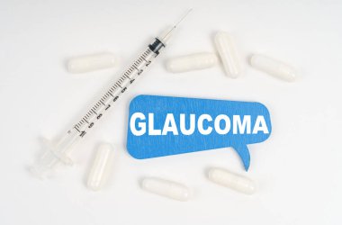 Tıp ve sağlık konsepti. Beyaz arka plan hapları, bir şırınga ve üzerinde GLAUCOMA yazan mavi bir plaka.