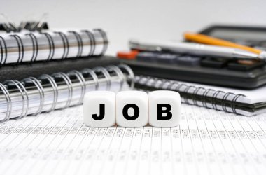 İş ve finans kavramı. Masanın üzerinde, ofis eşyalarının arasında, üzerinde yazı olan küpler - JoB