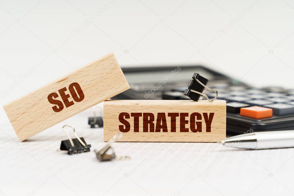 Business and finance concept. On a white background, a calculator, a pen, reports and wooden dies with the inscription - SEO STRATEGY