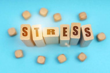 Tıp konsepti. Mavi arkaplanda, tahta küpler ve üzerinde STRESS yazan Jenga.