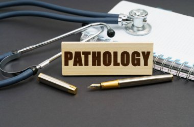 Tıp konsepti. Masanın üzerinde bir defter, bir steteskop ve üzerinde patoloji yazan bir tabela var.