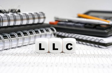 İş ve finans kavramı. Masanın üzerinde, ofis eşyalarının arasında, yazıtlı küpler - LLC