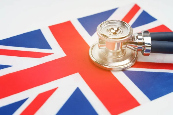医学と経済学の概念 英国の国旗に聴診器があります — ストック写真