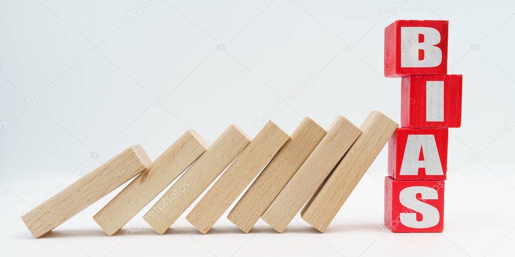 Business and economy concept. On a white background, wooden dice fell like dominoes, the fall was stopped by cubes with the inscription - BIAS
