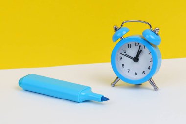Eğitim konsepti. Beyaz ve sarı arka planda, mavi alarm saati ve işaret var..