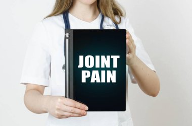 Tıp ve sağlık konsepti. Doktorun elinde bir tablet var, üzerinde Joint Paint yazıyor.