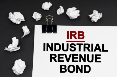 Sanayi konsepti. Siyah arka planda, üzerinde IRB-Endüstriyel Gelir Tahvili yazan buruşuk kağıt ve kağıt parçaları var.