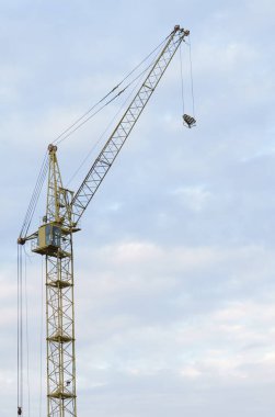 İnşaat makineleri. Gökyüzünün arka planında bulutlu bir vinç.