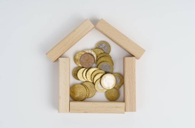 İş konsepti. Beyaz arka planda, tahtadan yapılmış küçük bir ev, madeni paranın içinde..
